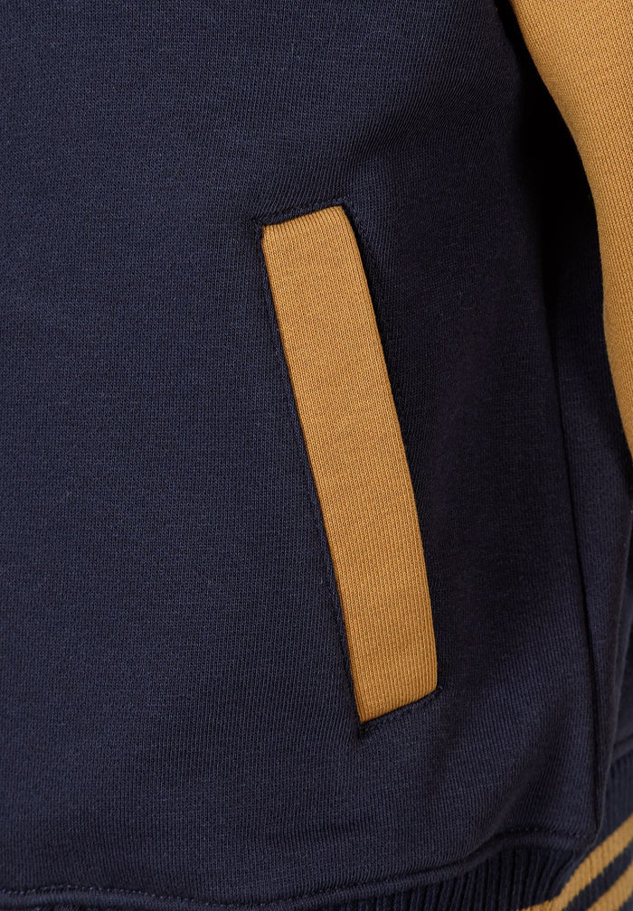 Close-up of a navy baseball jacket with contrasting yellow pocket.
