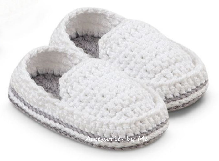 A pair of white crocheted baby booties with gray trim and gray lining.