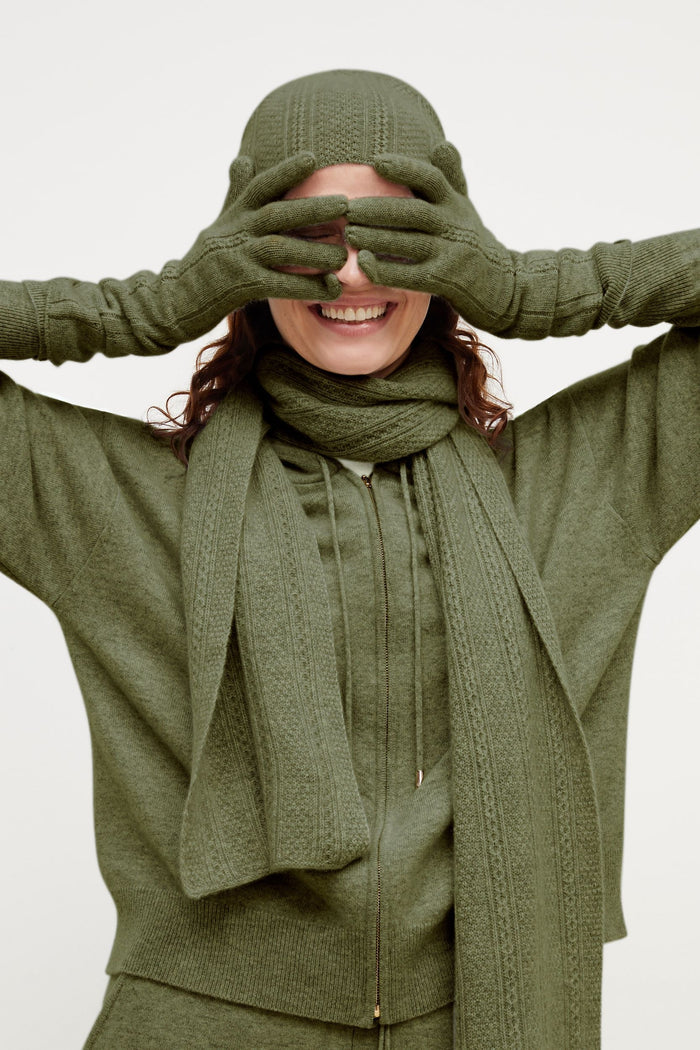 Front image of a woman standing wearing the Circle Cable Beanie—Cashmere in Olive | Grid Hover | Exclude