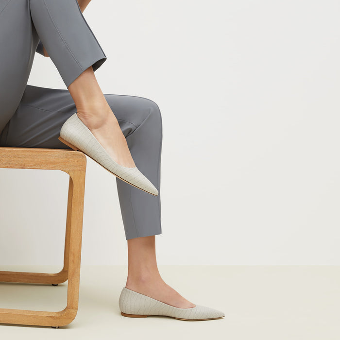 Side image of a woman sitting wearing the Rowan Flat—Embossed Croc in Gray