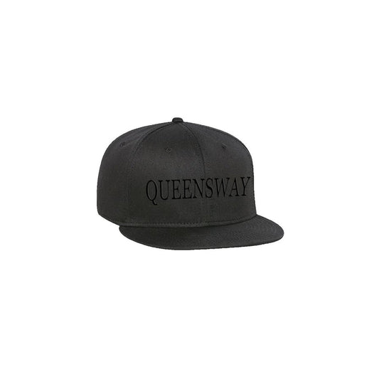 A black Queensway snapback cap with QUEENSWAY in bold black uppercase letters on the front, displayed against a plain white background.