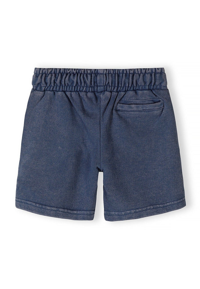 Detail of boys' blue acid wash shorts with elastic waistband and side pocket.