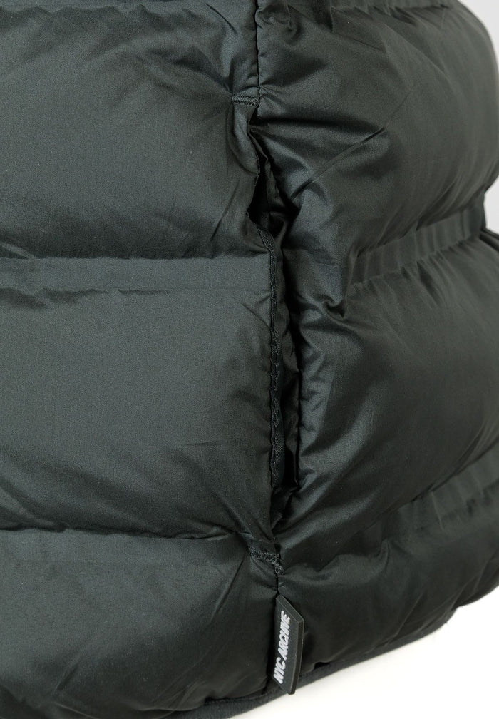 Detail of a boys' quilted sleeveless waistcoat in olive with padded insulation and logo tag.