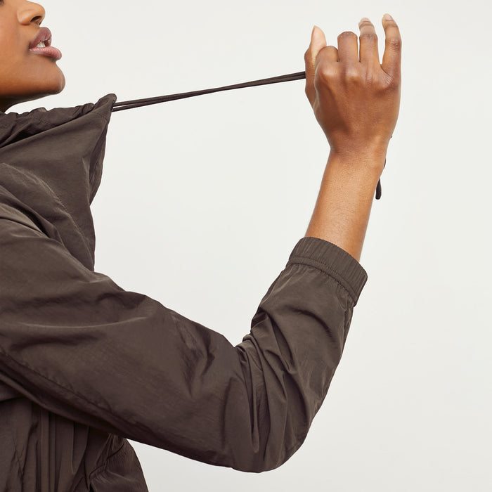 Side image of a woman standing wearing the Britt Hoodie—AirTech in Dark Moss
