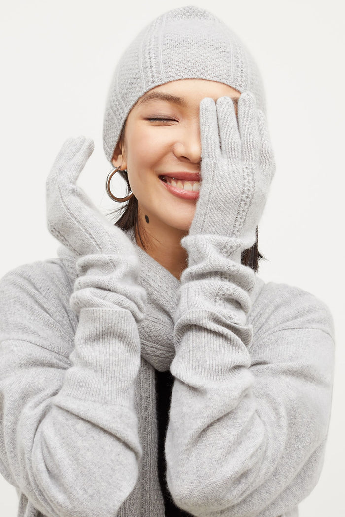 Front image of a woman standing wearing the Circle Cable Beanie—Cashmere in Heather Gray | Grid Hover | Exclude