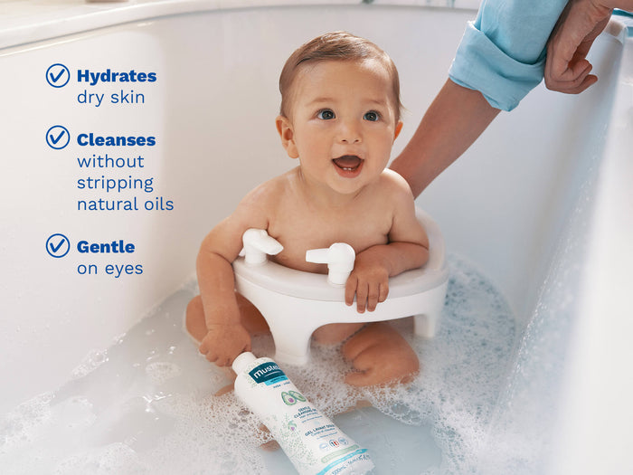 Mustela USA | Smiling baby sitting in a bath seat holding a bottle of cleansing gel.