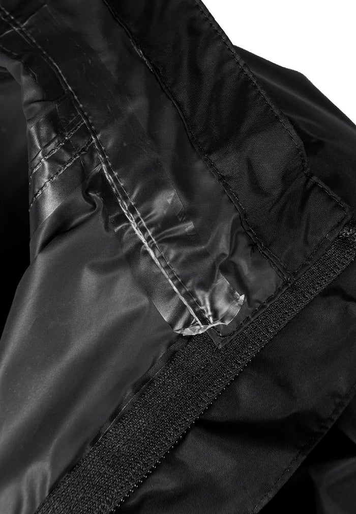 Detail of a black waterproof jacket showing the inner lining and velcro closure.