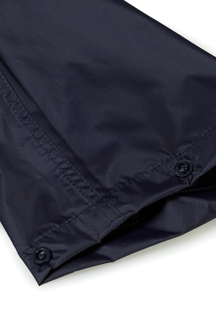 Detail of navy waterproof overpants with button closure and elasticated ankle cuffs.
