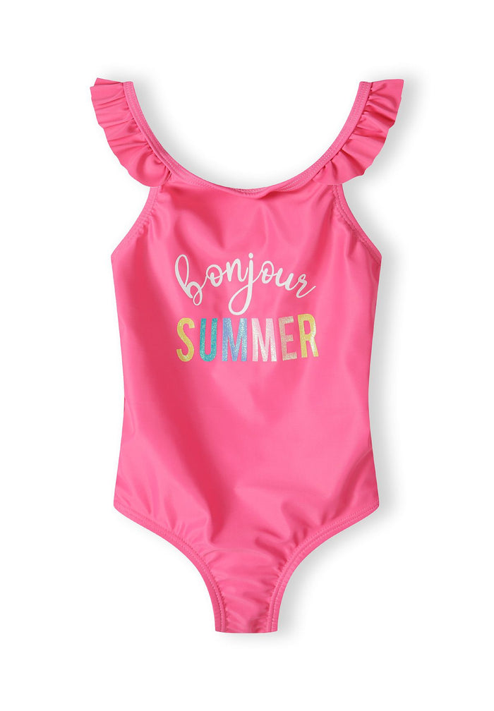 Girls one-piece swimsuit in pink with ruffled straps and 'bonjour SUMMER' print, front view.