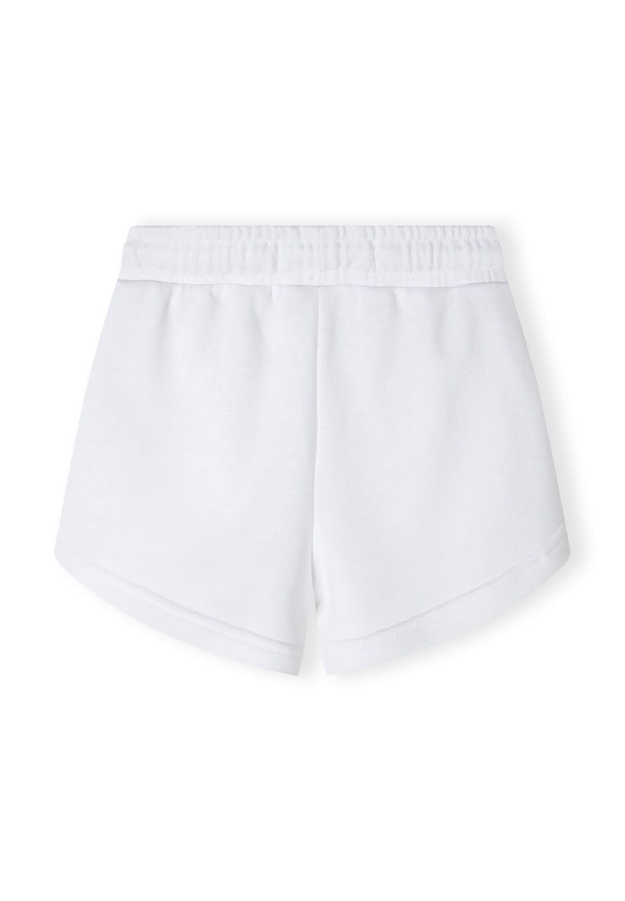 Detail of white shorts with elasticated waistband and rounded edges.