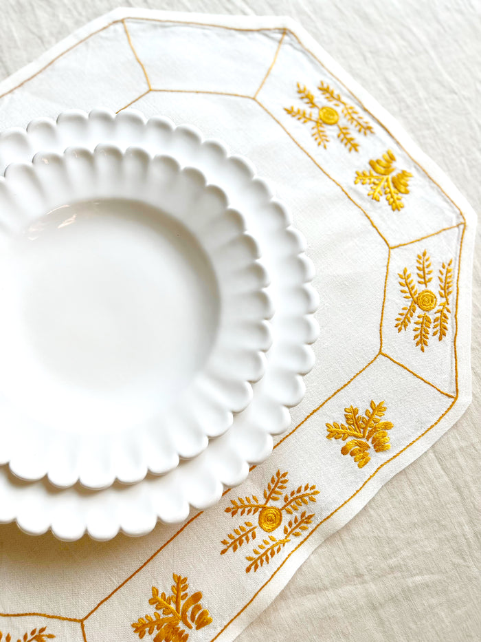 octagonal white linen placemat with gold embroidery 19.5" by 16" with white plates