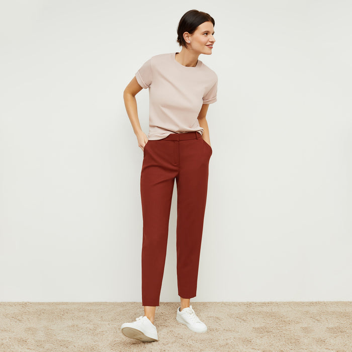 Front image of a woman standing wearing the mejia pant in sharkskin in rust | Lead