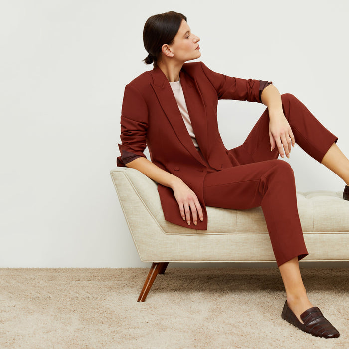 Side image of a woman standing wearing the mejia pant in sharkskin in rust