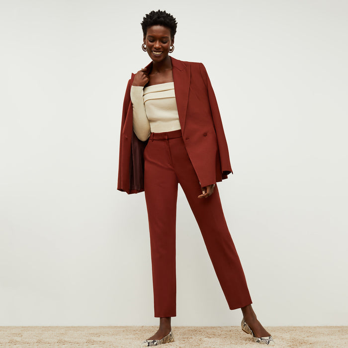 Front image of a woman standing wearing the mejia pant in sharkskin in rust