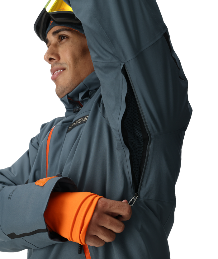 Person wearing a gray jacket with orange accents, standing against a white background