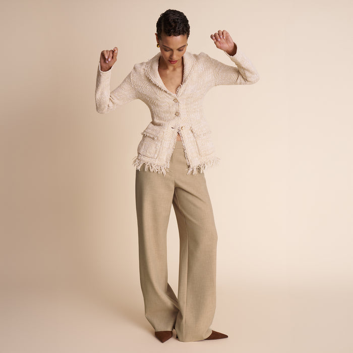 Woman wearing a beige outfit with a textured top and wide-leg pants on a beige background