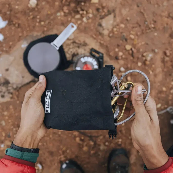 Person holding a black Primus carry sack whilst removing a Primus Express Spider Camping Gas Stove