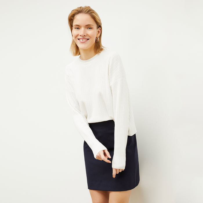 Front image of a woman standing wearing the tyler sweatshirt in ivory | Lead