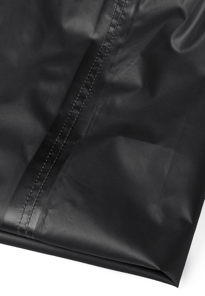Detail of black waterproof overpants with visible stitching.