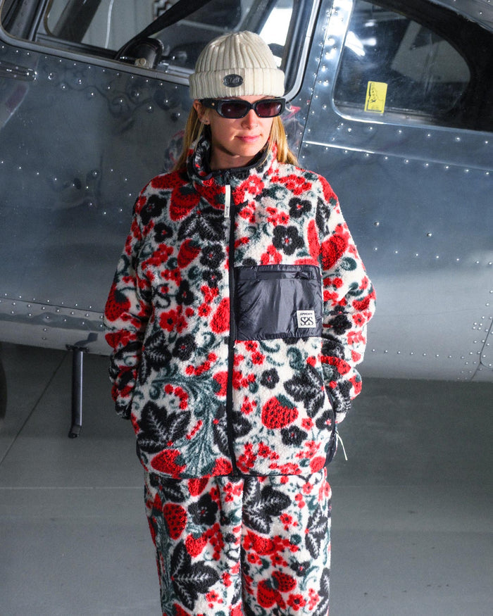 Person wearing a colorful floral jumpsuit standing in front of a helicopter.