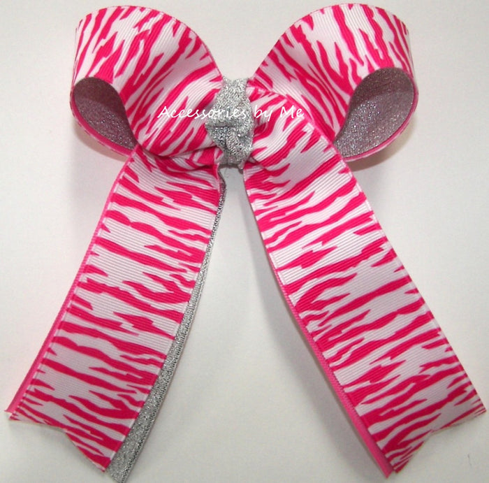 A large hair bow featuring a hot pink and white zebra print pattern with a glittery silver center and silver inner loops, set against a plain white background.